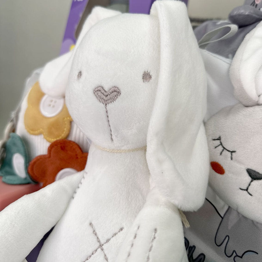 A white BABY'S FIRST GIFT SET stuffed animal is sitting on a shelf.