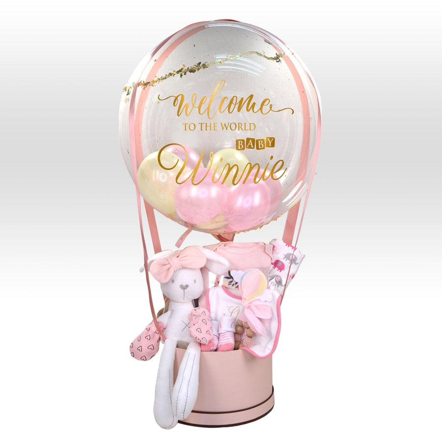 A pink VWOWGIFTS Hot Air Balloon of Love Baby Girl Hamper with a teddy bear inside, perfect for baby gifts or newborns.