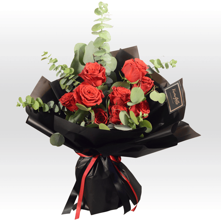 A bouquet of ROSE WHISPERER red roses wrapped in black paper by VWOWGIFTS.