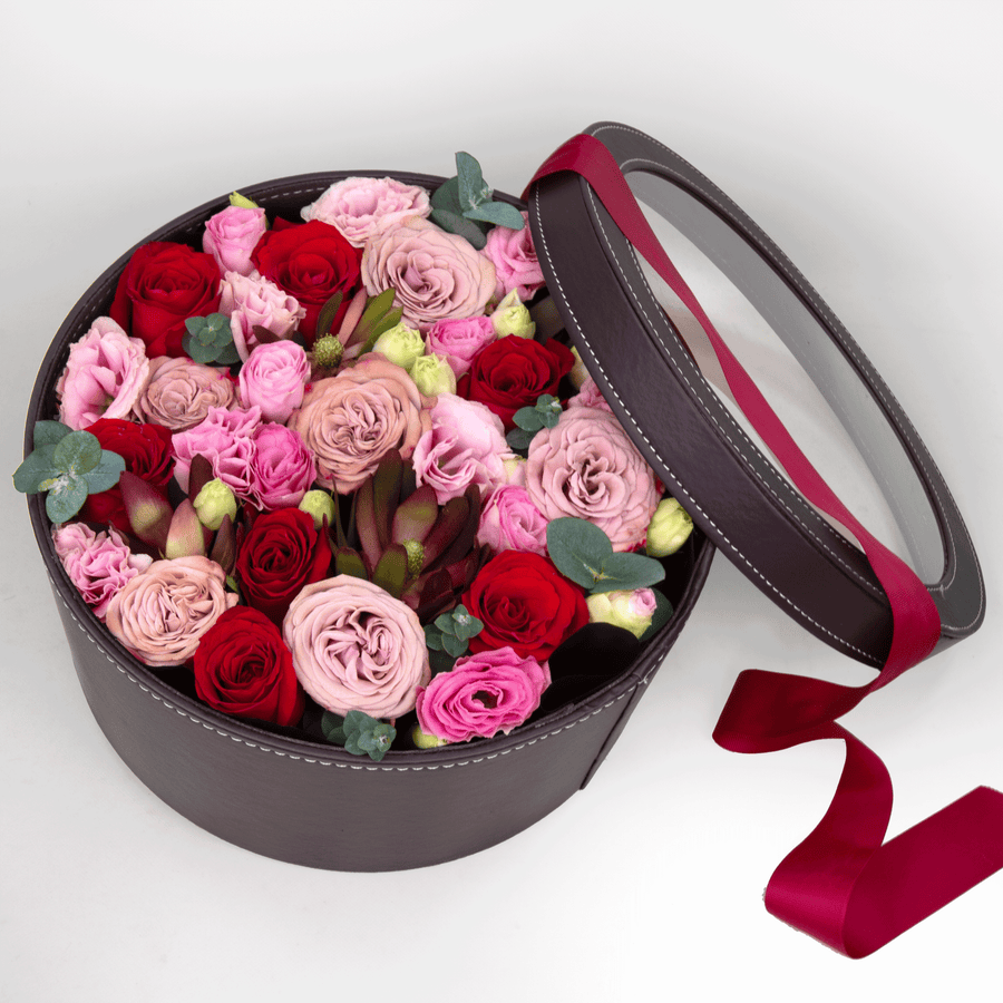 A round box filled with Whispering Love pink and red roses by VWOWGIFTS.