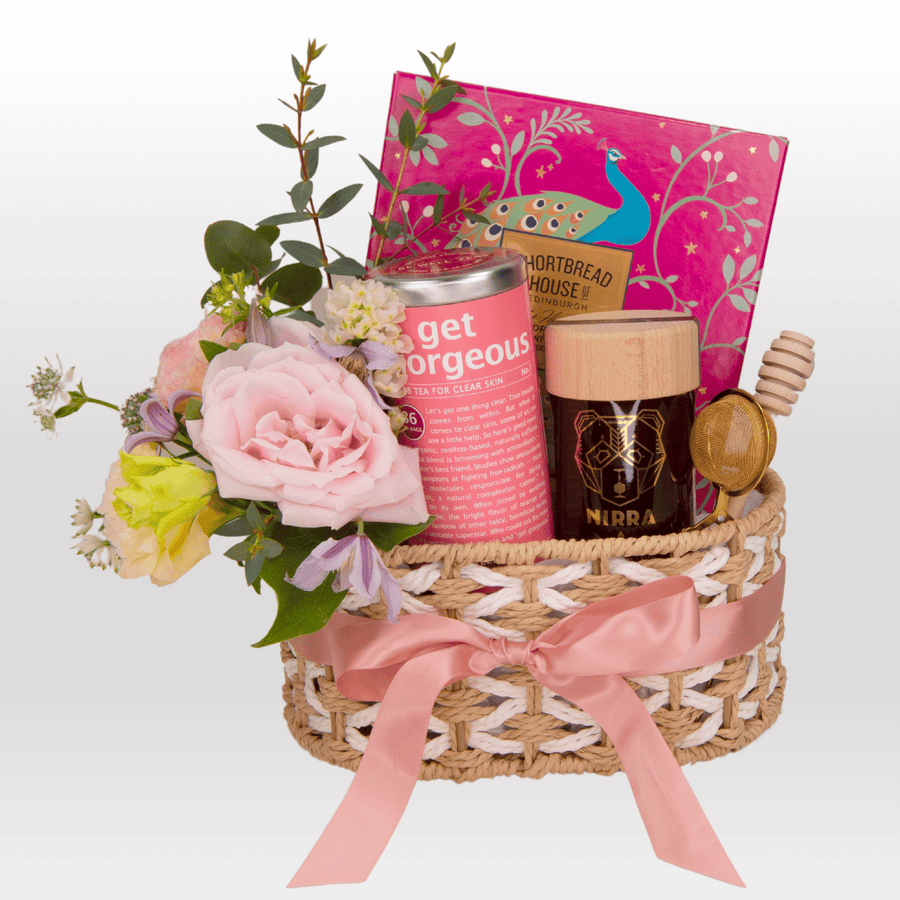 A VWOWGIFTS wicker basket filled with MODERN ROMANTICS flowers and a book.