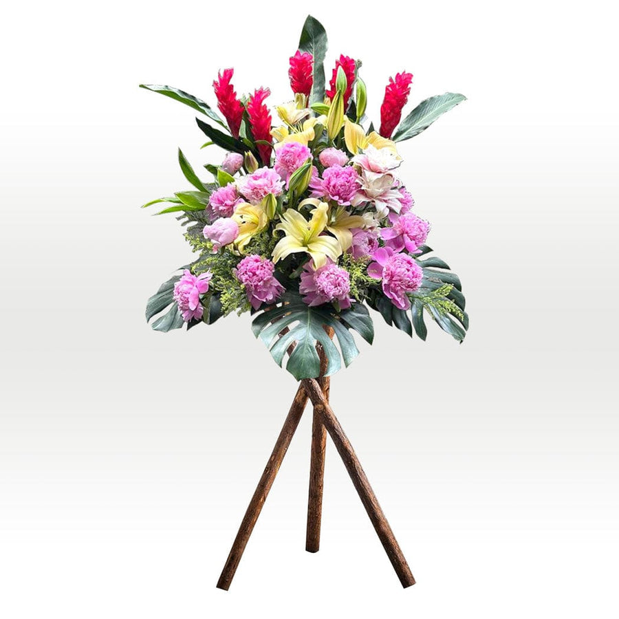 An arrangement of Joyous Celebration flowers on a VWOWGIFTS wooden stand.