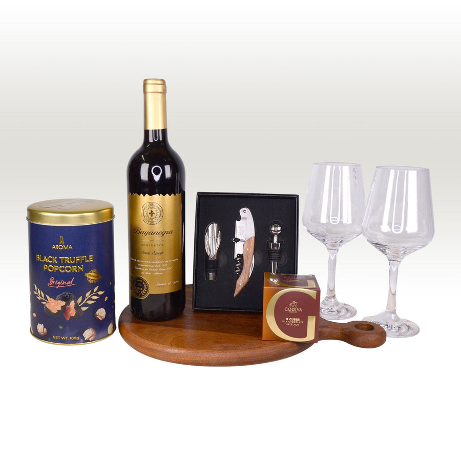 A VWOWGIFTS hamper featuring a bottle of TIMELESS INDULGENCE wine, a wine glass, a cheese board, and a tin.