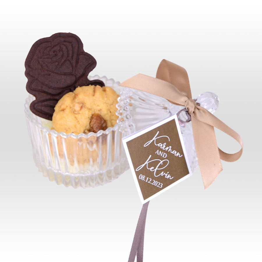 A JOYOUS MOMENTS WEDDING FAVOUR WITH CRYSTAL GLASSWARE BOX - HANDMADE COOKIES by VWOWGIFTS in a glass container with a ribbon.