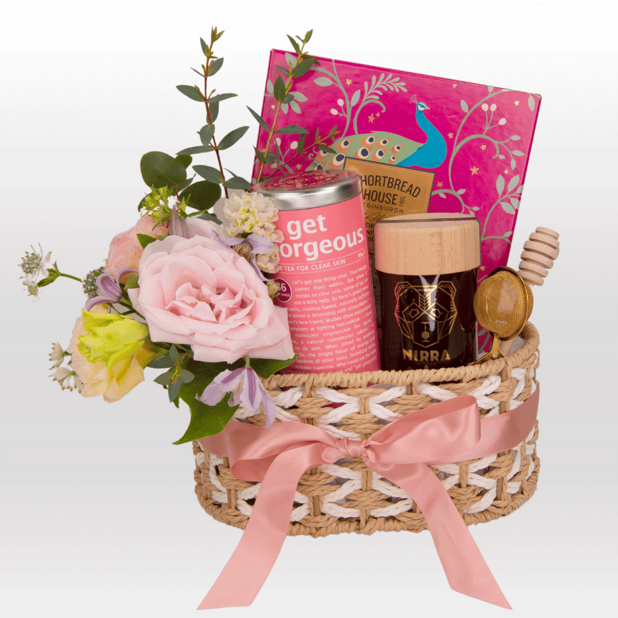 A VWOWGIFTS wicker basket filled with MODERN ROMANTICS flowers and a book.
