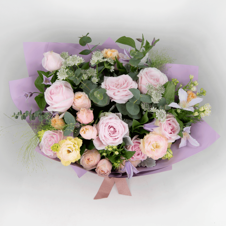 A bouquet of pink roses wrapped in purple paper, JUST FOR YOU by VWOWGIFTS.
