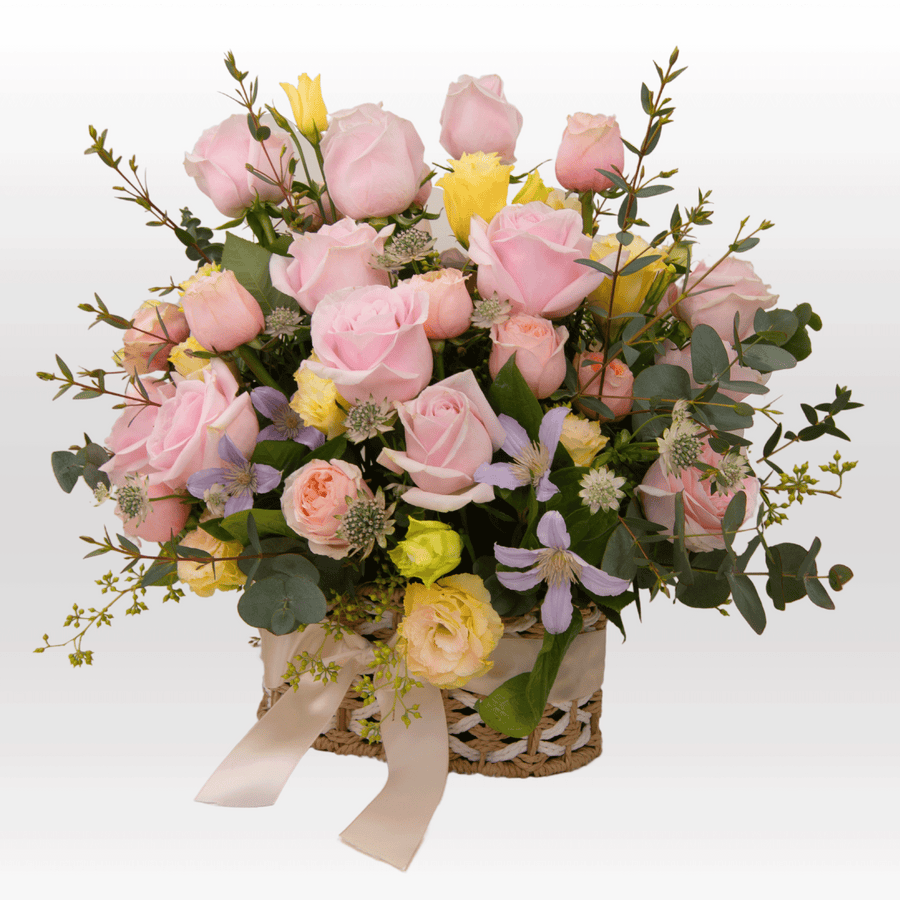 A Sweet Vibes wicker basket filled with pink and yellow roses from VWOWGIFTS.