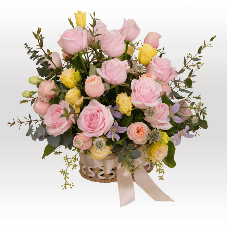 A basket filled with SWEET VIBES pink and yellow roses by VWOWGIFTS.
