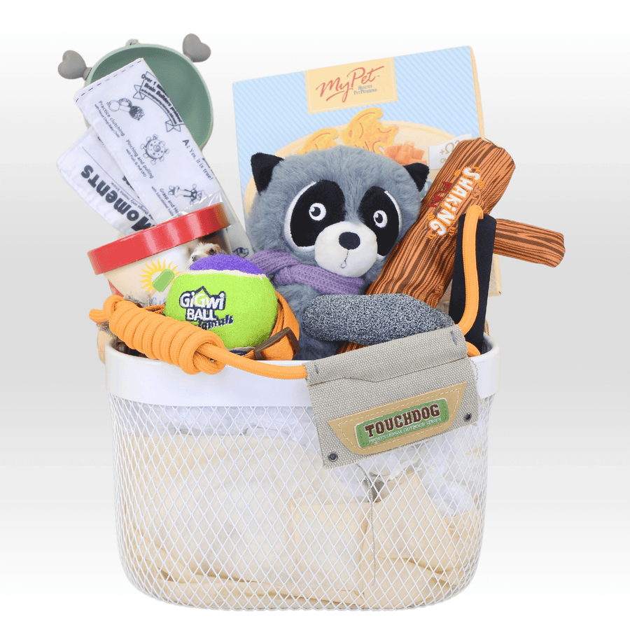 A basket with a UNIQUE PET GIFT BOX from VWOWGIFTS, raccoon, dog toys, and other items.